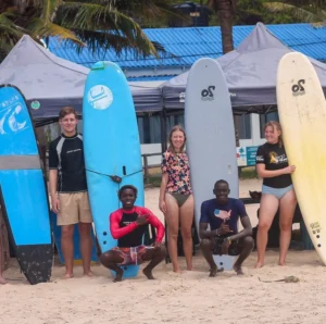 A cheerful group of surf students and instructors posing with their boards at Tofo Beach after completing a fun-filled lesson with Wutsita Surf School, Mozambique.